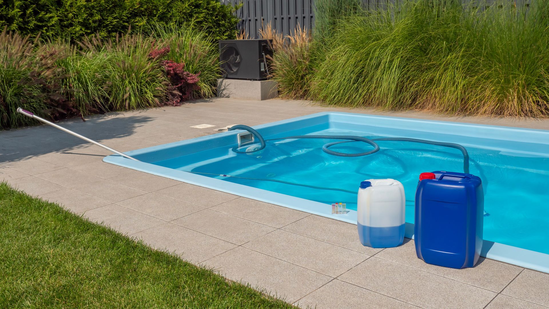 A swimming pool is being cleaned with chemicals and a hose.