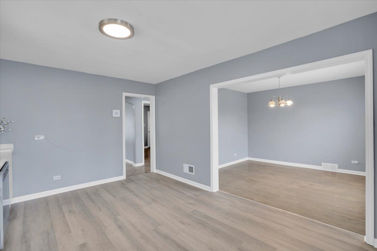 Empty room with gray walls, light wood floor, and doorway leading to another room.