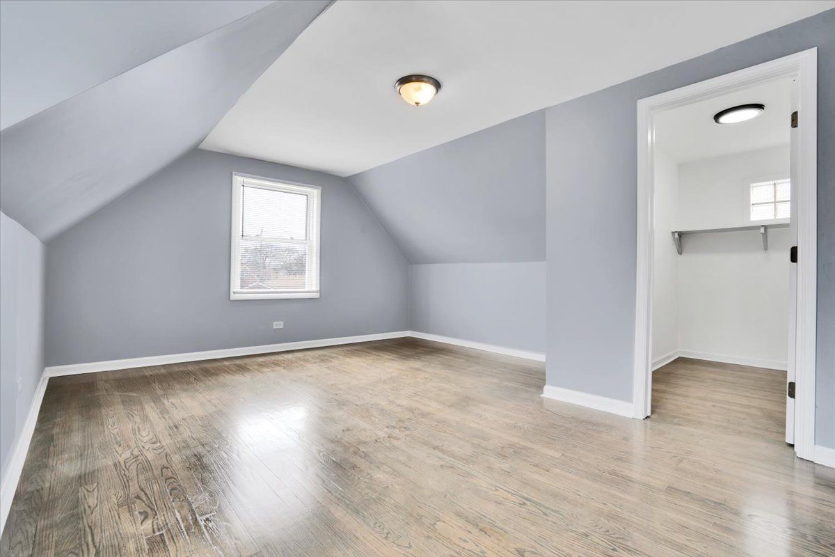 Empty room with gray walls, hardwood floor, window, and closet.