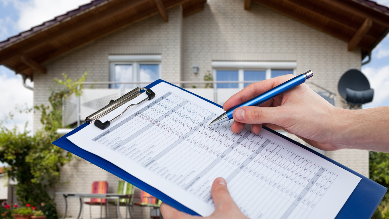 Person writing on clipboard in front of a house, likely a home inspection.
