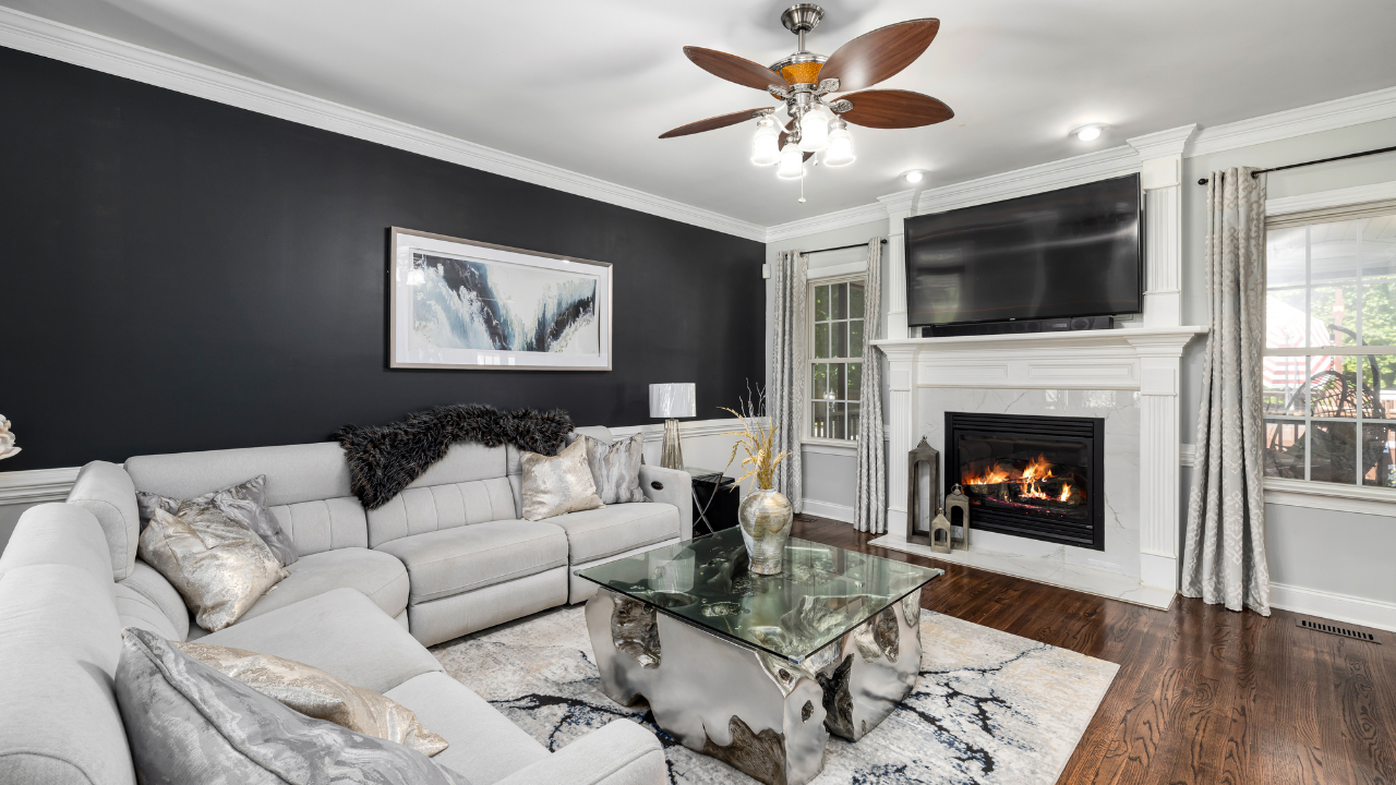 Woman in a suit smiling at two people at a table, likely in a business meeting. City view in background.