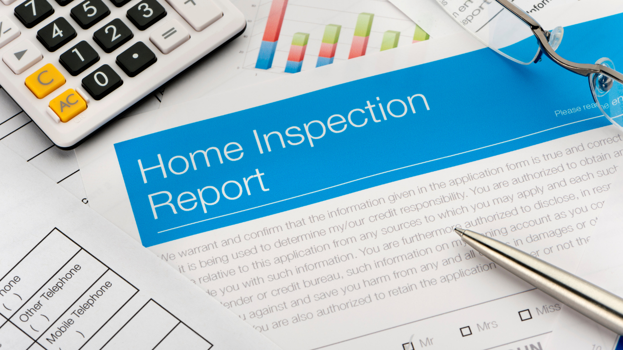 Home inspection report with calculator, pen, and eyeglasses on a desk.