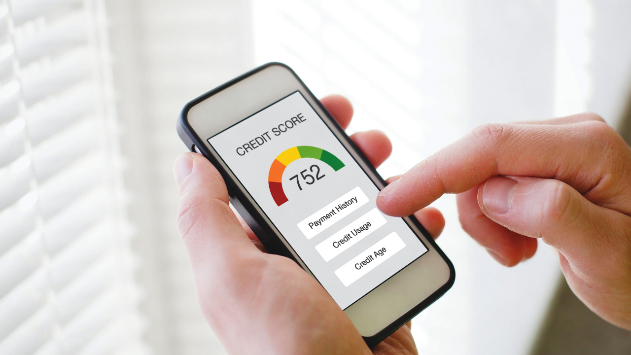 Person holding smartphone displaying a credit score of 762; green, yellow and red gauge.