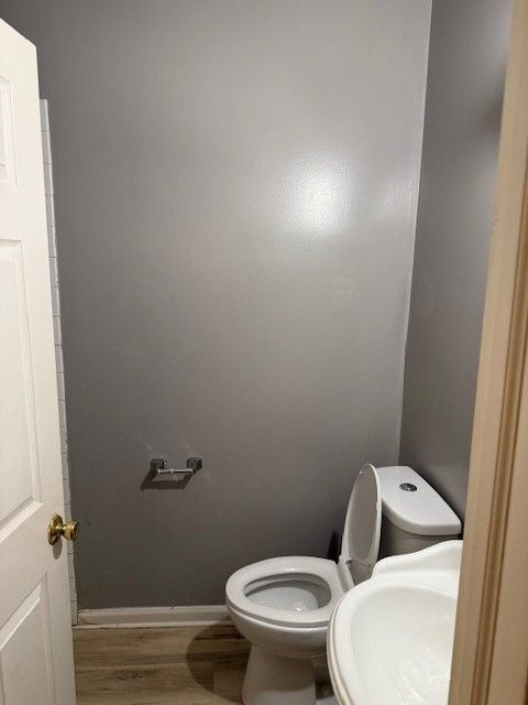 Small bathroom with a toilet, sink, and gray walls.