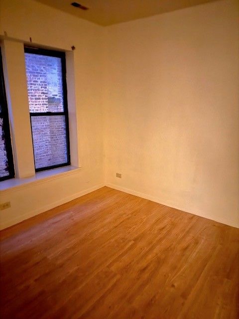 Empty room with wood-look flooring, window, and off-white walls.