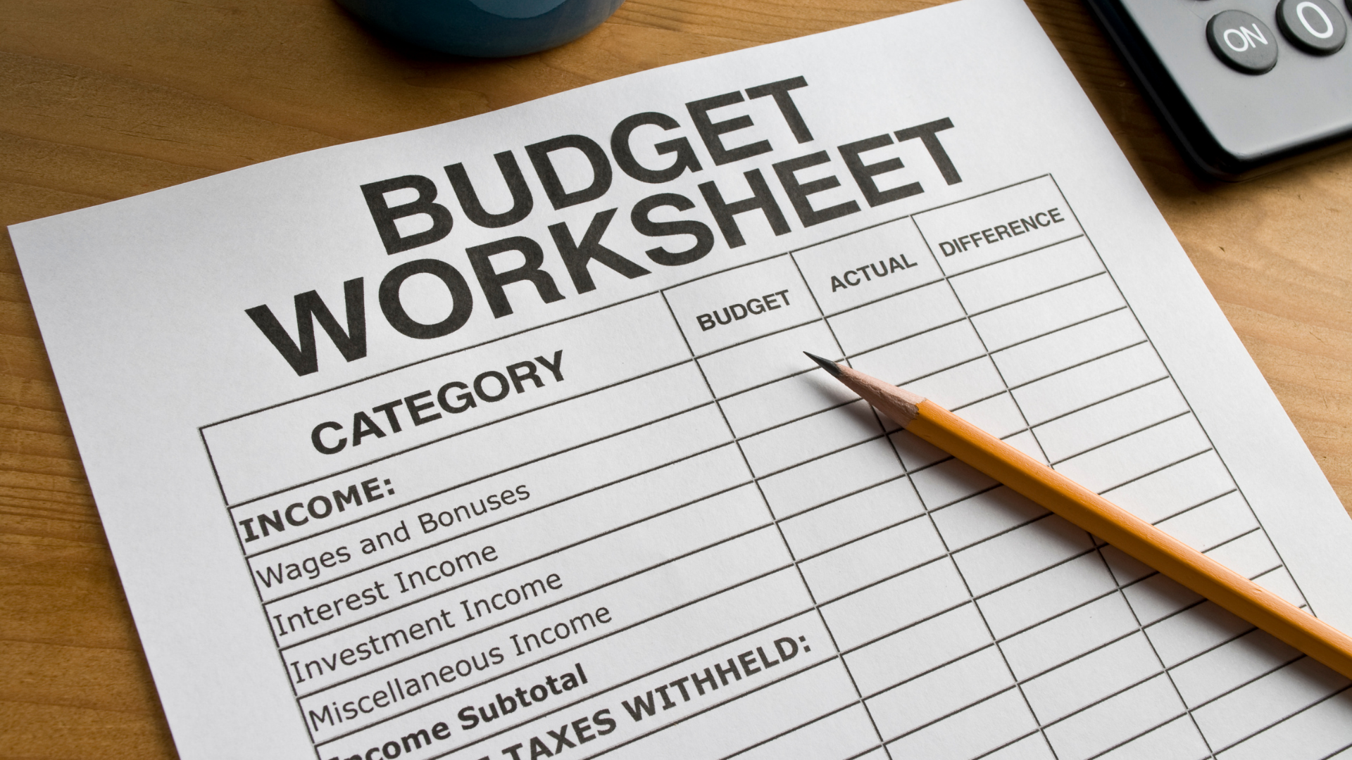 Budget worksheet with pencil on a wooden desk.