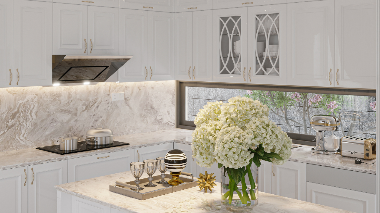 White kitchen with marble countertops, cabinetry, and a floral arrangement.