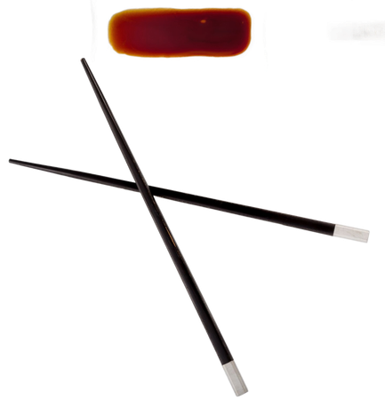 Due bacchette nere con le punte argentate incrociate sopra una piccola pozzanghera isolata di salsa di soia marrone su sfondo bianco.