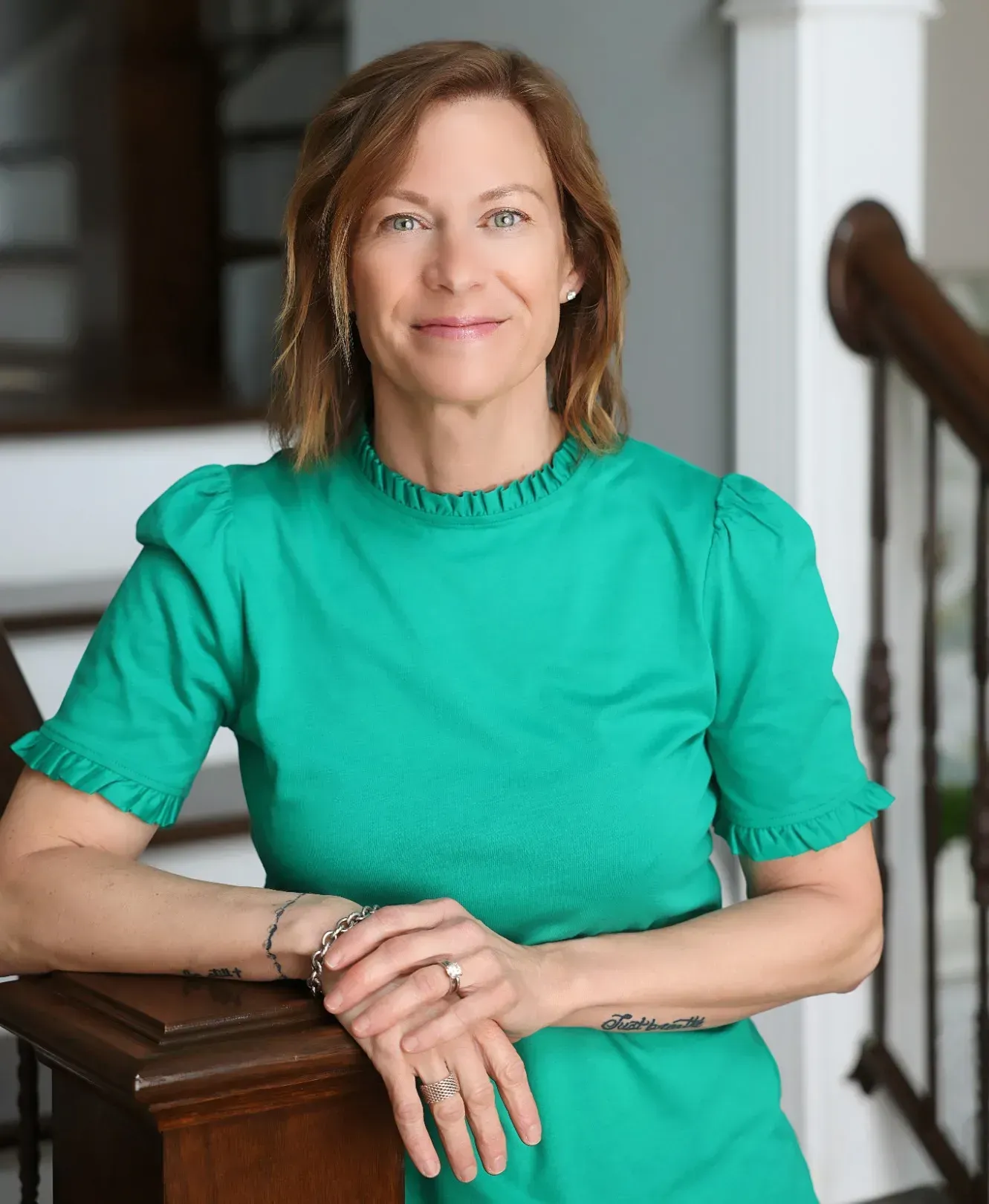 A woman in a green shirt is leaning on a wooden railing.