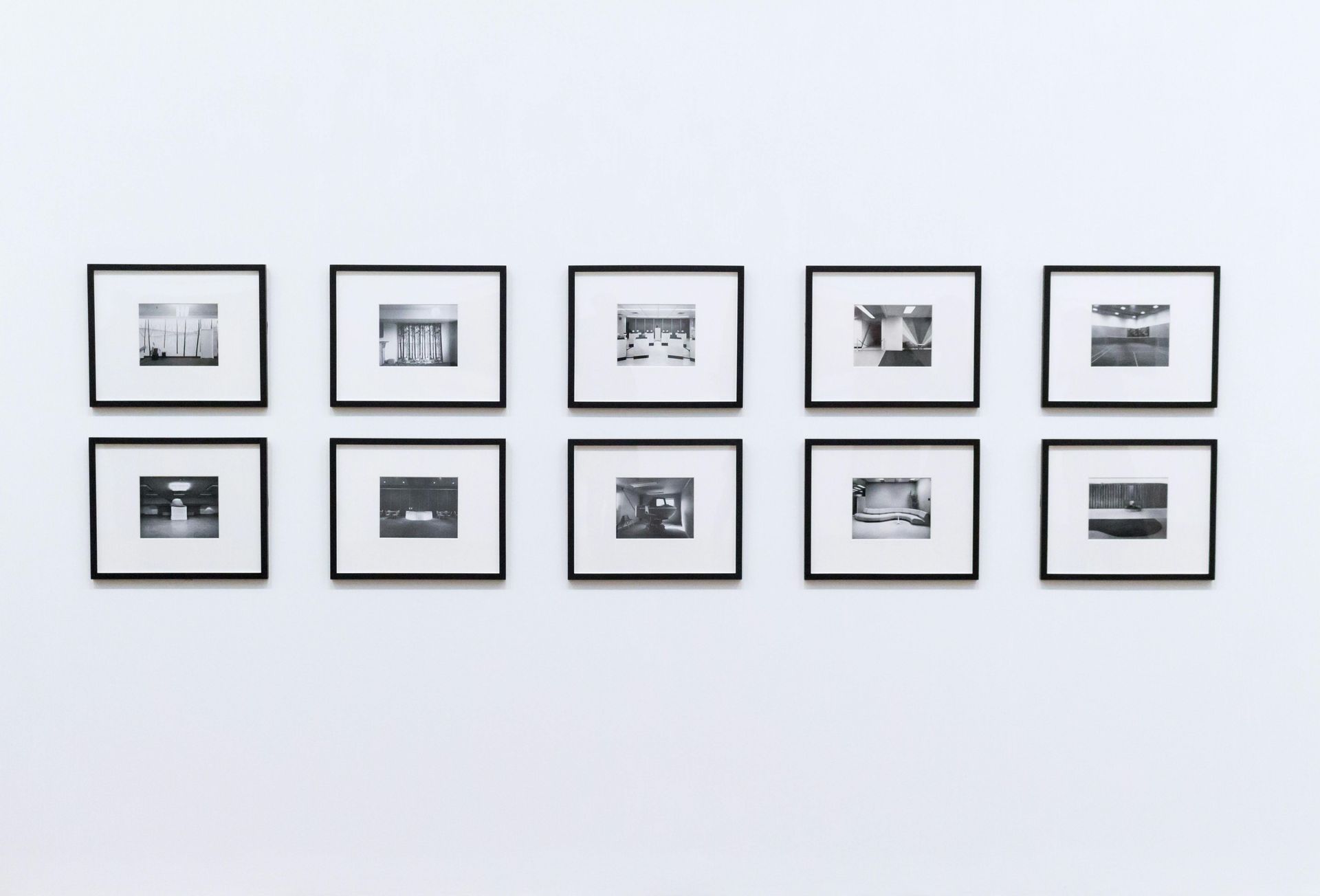 A row of black and white pictures are hanging on a white wall.