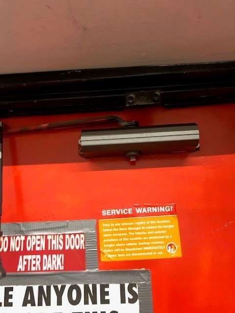 A red door with a service warning sticker on it