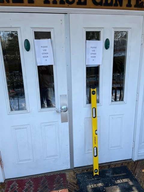 A yellow level is sitting in front of a white door.