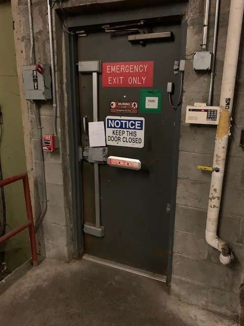 A black door with a red sign on it that says emergency exit only.