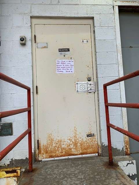 A white door with a red railing and a sign on it