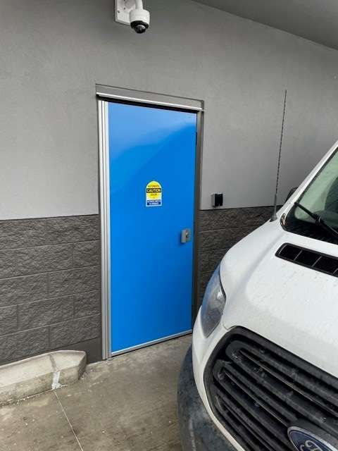 A white van is parked in front of a blue door.
