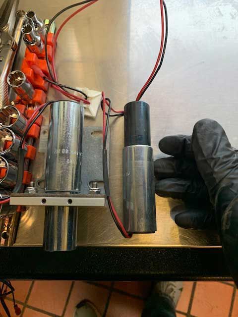 A person wearing black gloves is holding a metal object on a table