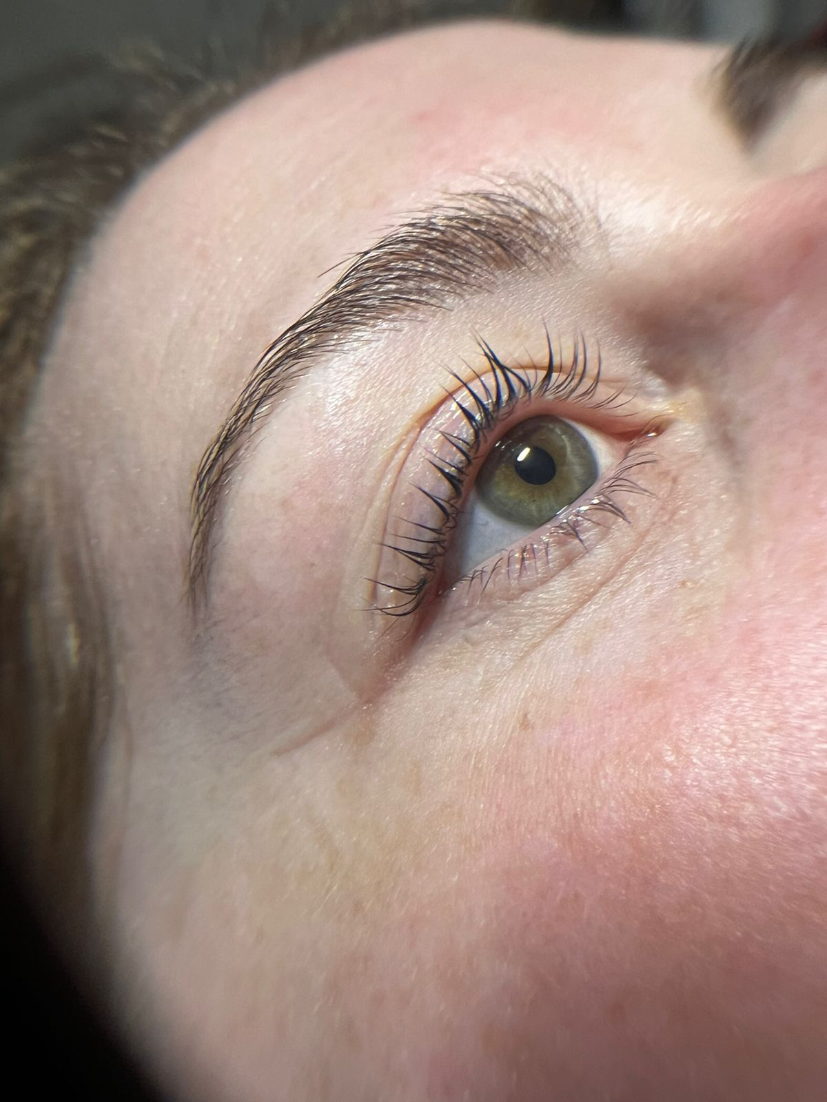 a woman is getting her eyebrows painted by a makeup artist .