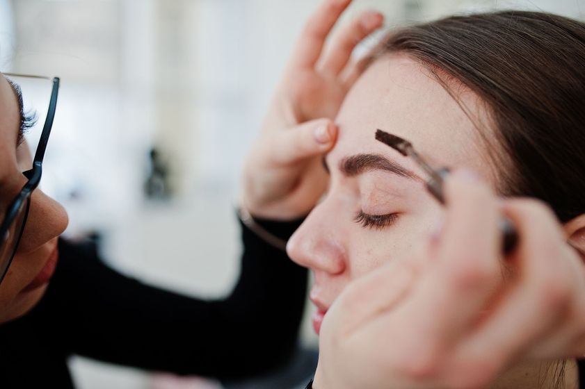 a woman is getting her eyebrows done by a makeup artist .