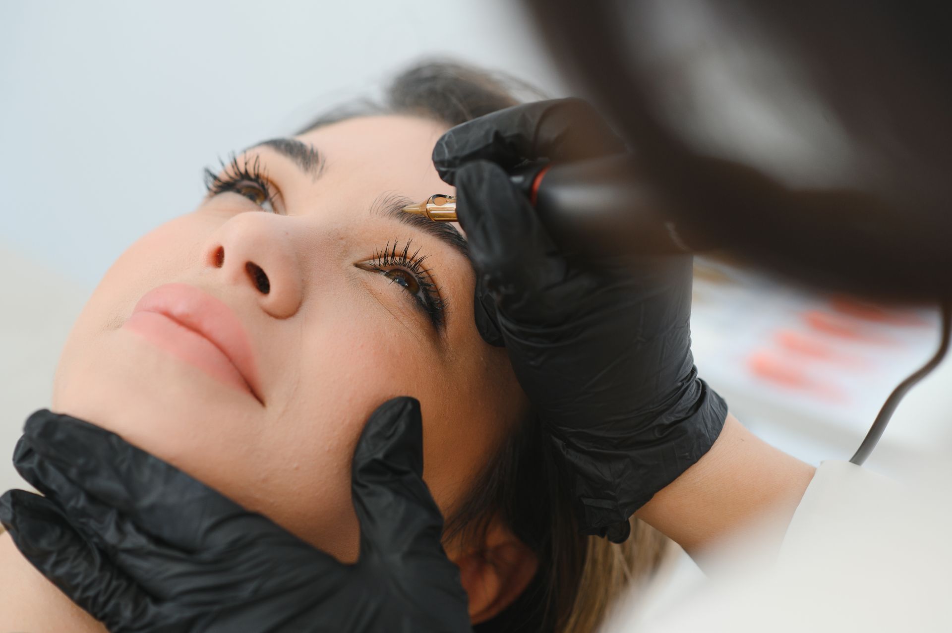 a woman is getting her eyebrows tattooed by a tattoo artist .