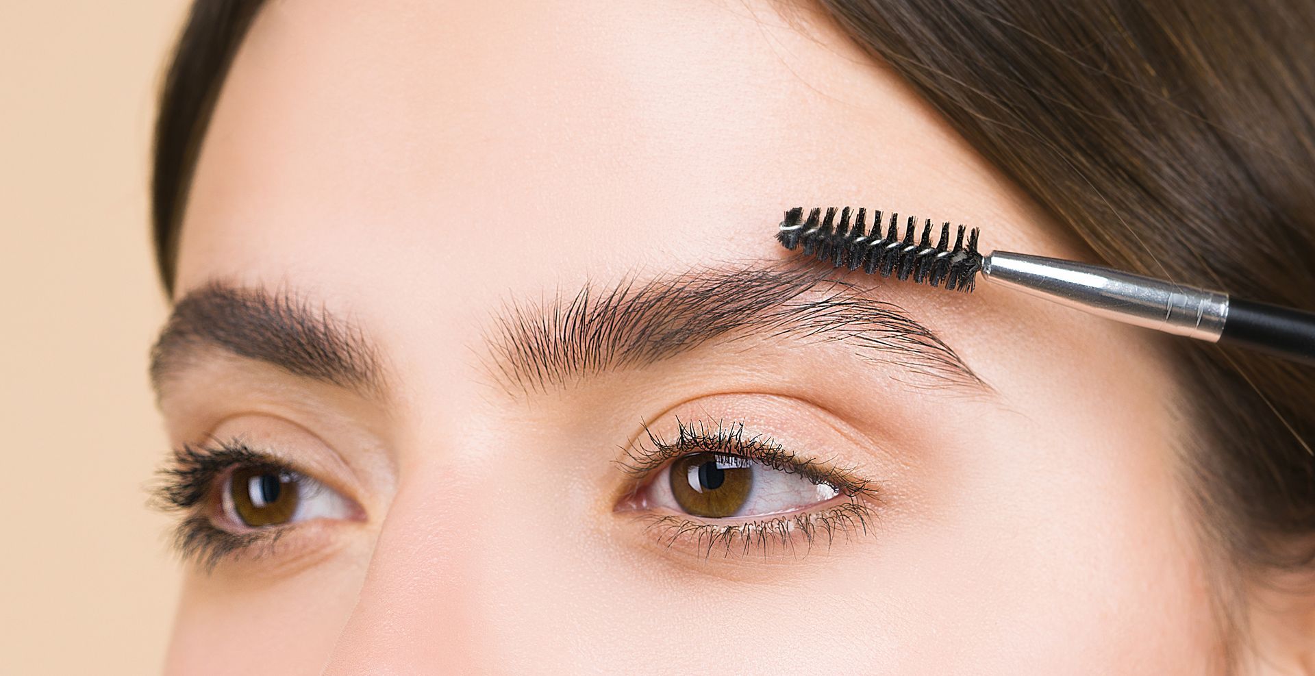 A woman is brushing her eyebrows with a brush.