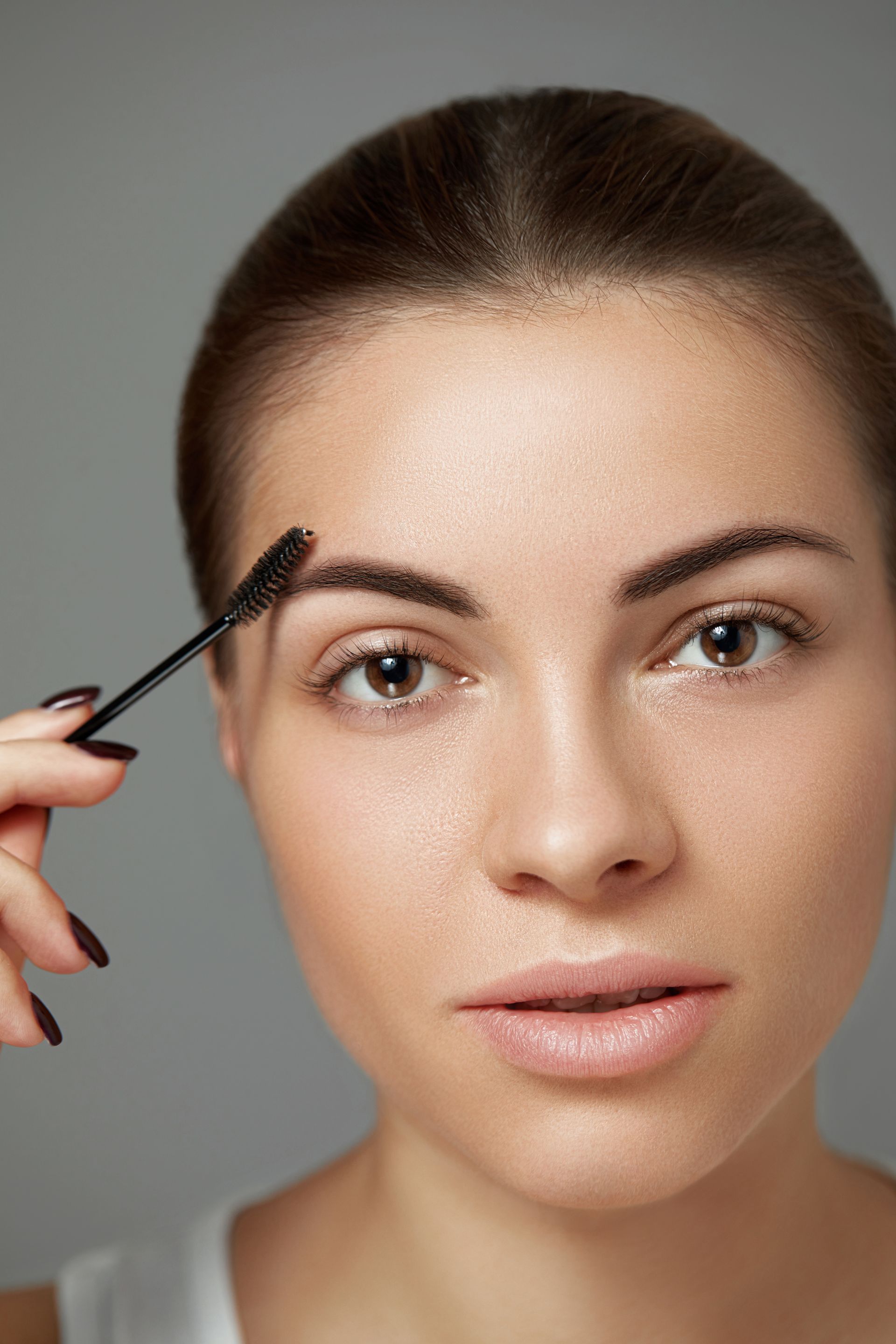 a woman is applying mascara to her eyebrows .