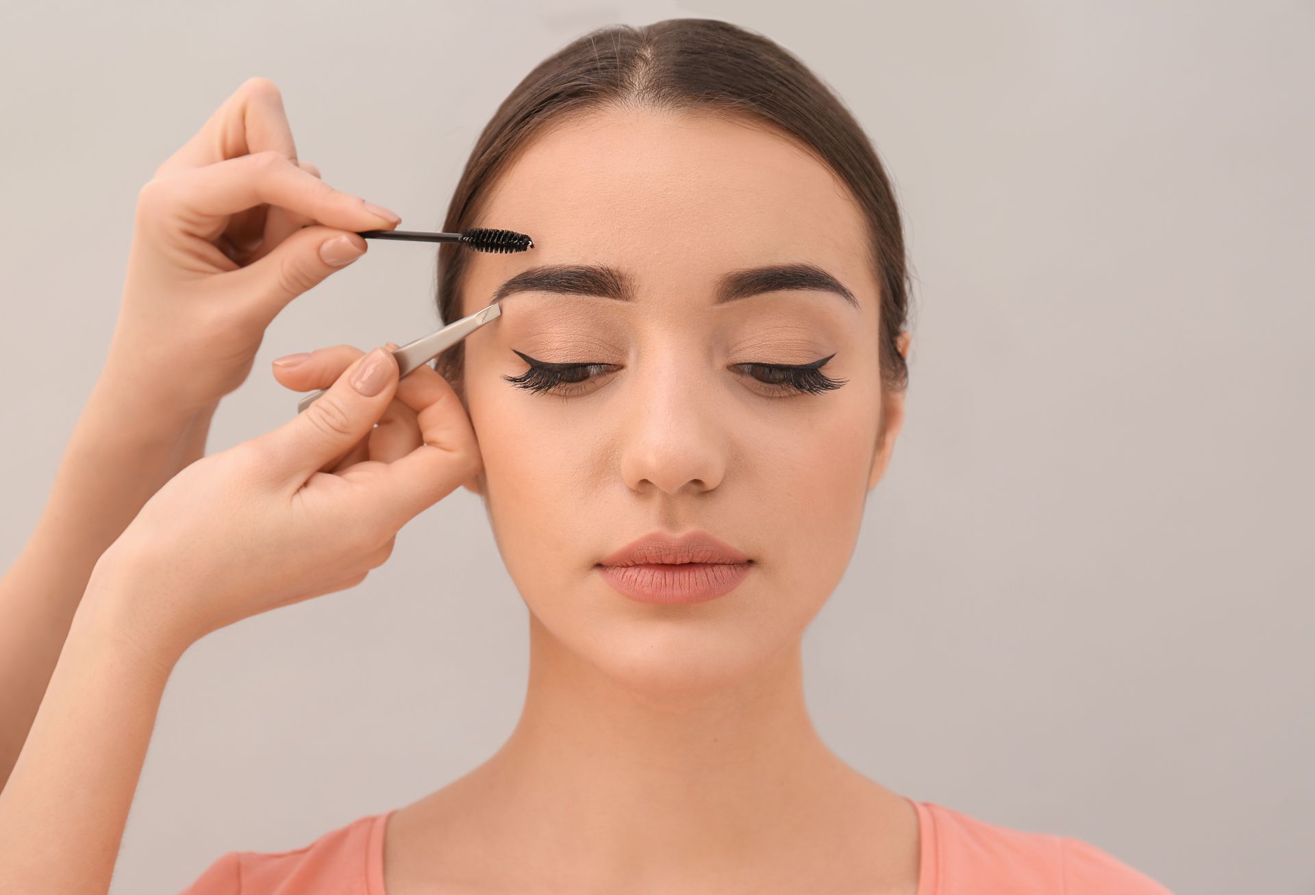 a woman is getting her eyebrows done by a makeup artist .