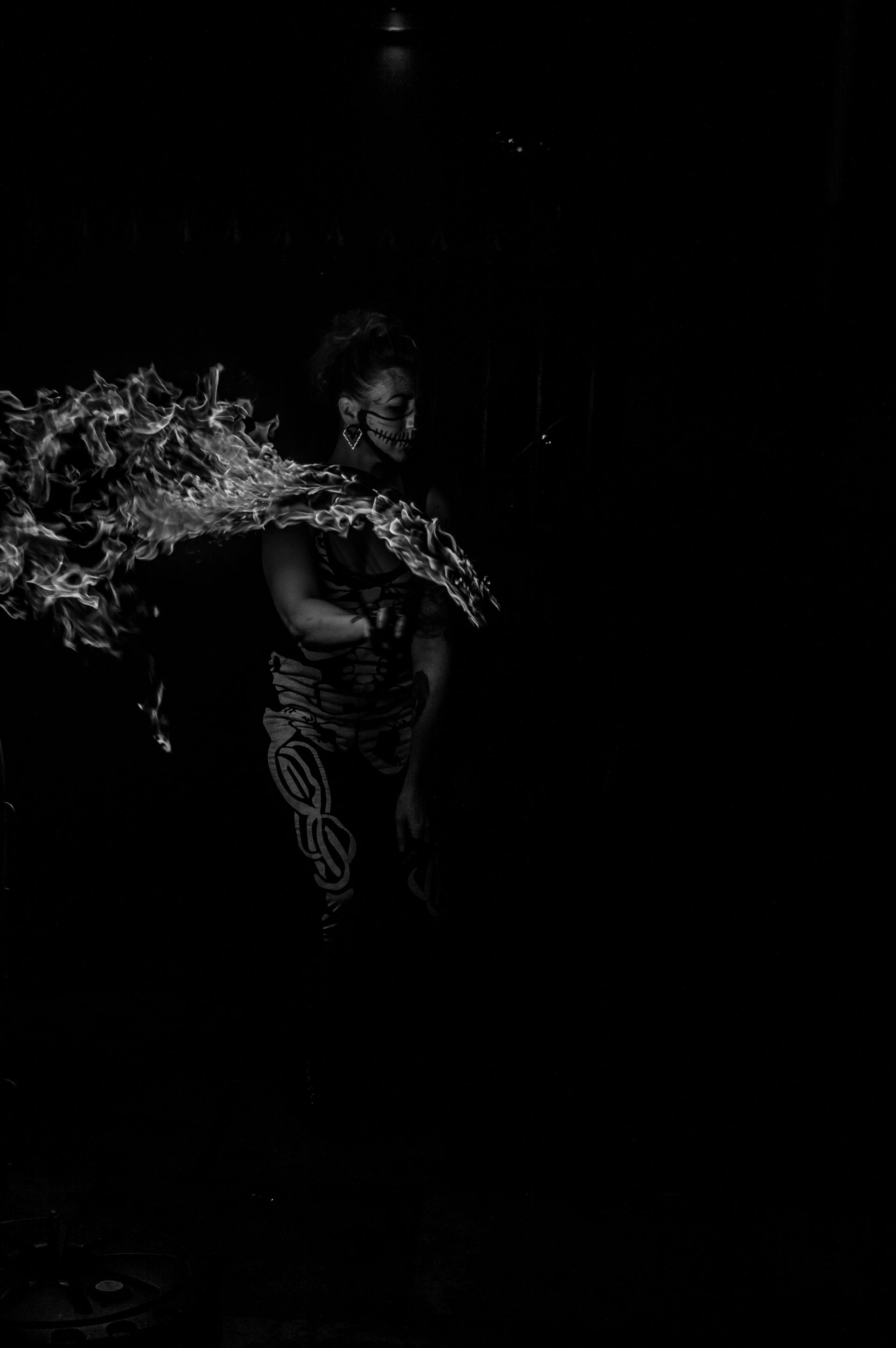 Black and White photo of Mia Meow with a long trail of flames in front of her dressed in a halloween skeleton costume and face paint by Powederkeg Photograhy