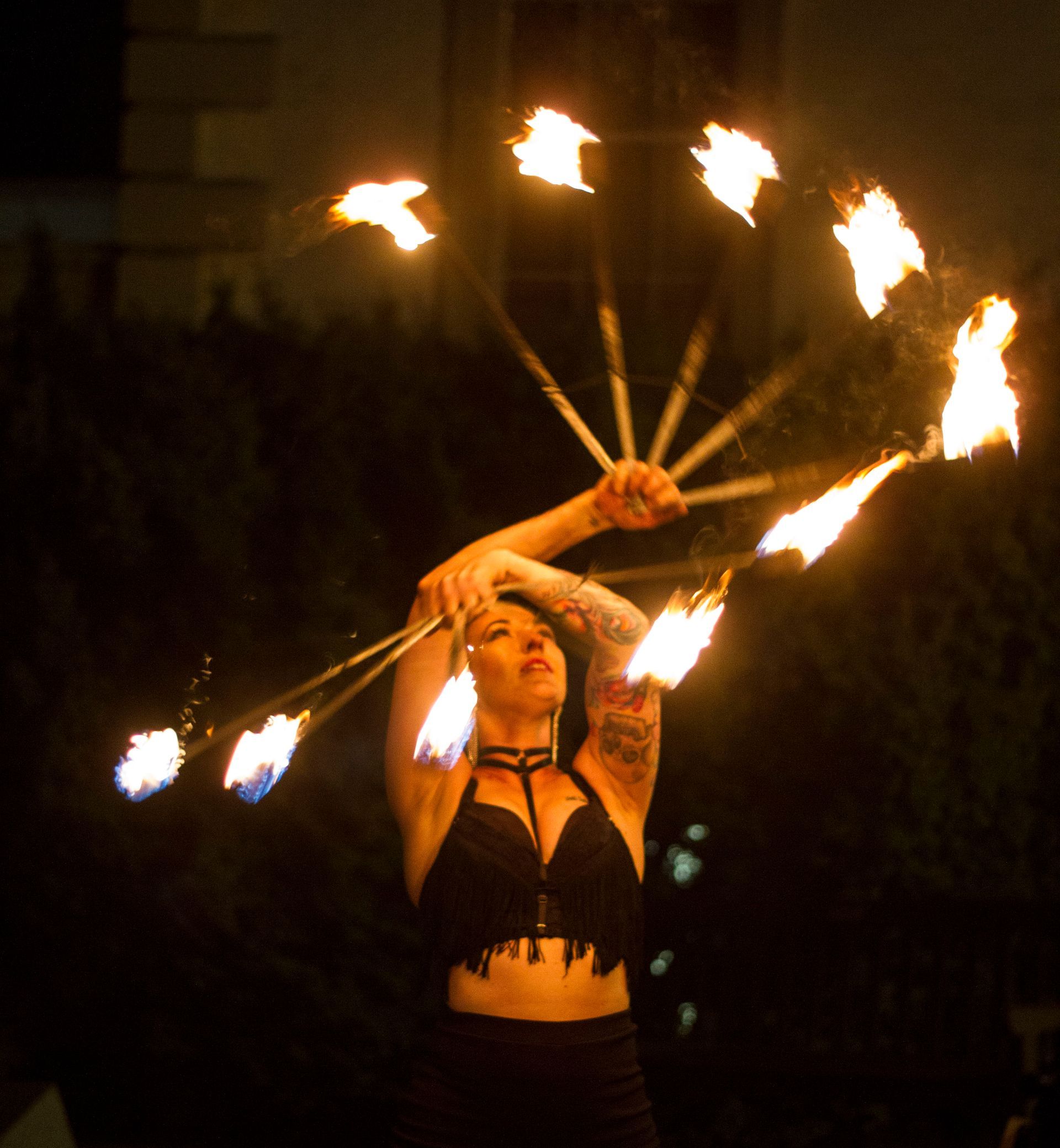 a colour photo of Mia Meow with her arms above her head with a splayed fire fine in each hand mid-spin by Raymond Garrett
