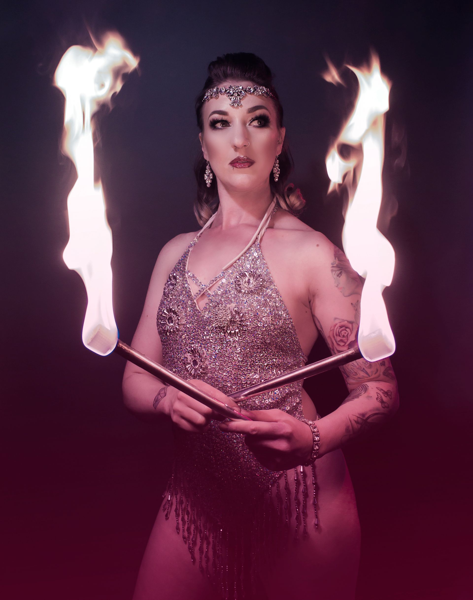 a colour image of Mia Meow with two fire wands crossed at her hands with the large flames from each end of the wand rising up beside her, she is posed in this still image by Snookie Mono Fauxtography