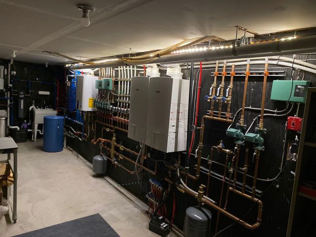 A room with a lot of pipes and boxes on the wall.