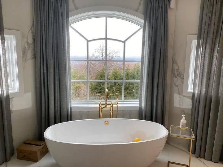 A bathroom with a bathtub and a large window.