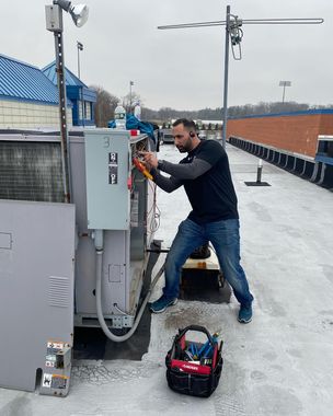 A man is working on a machine in the snow.