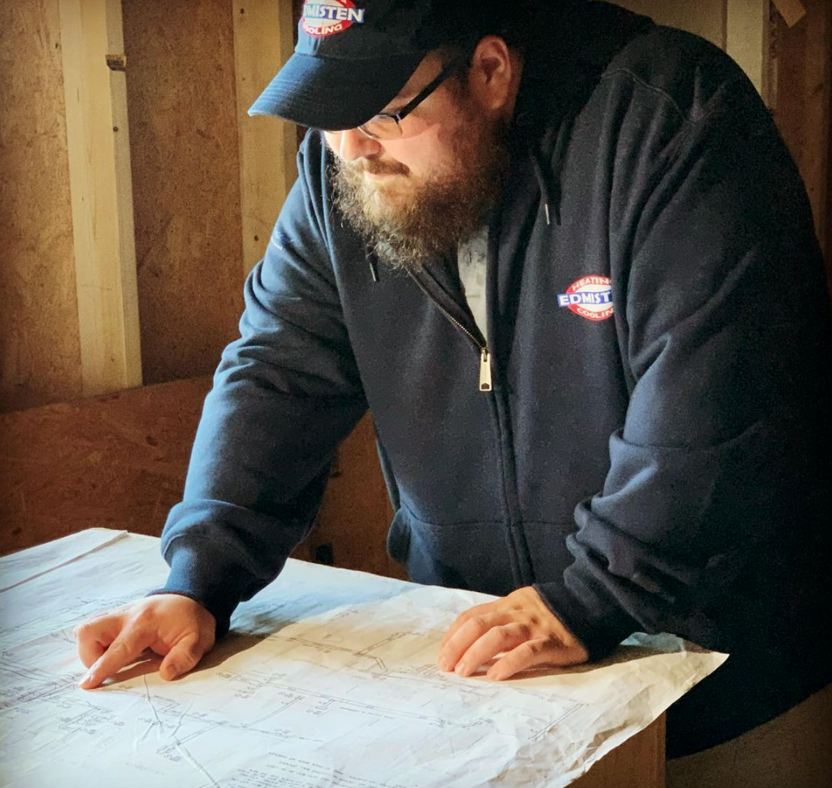 A man with a beard wearing a dickies hat is looking at a map
