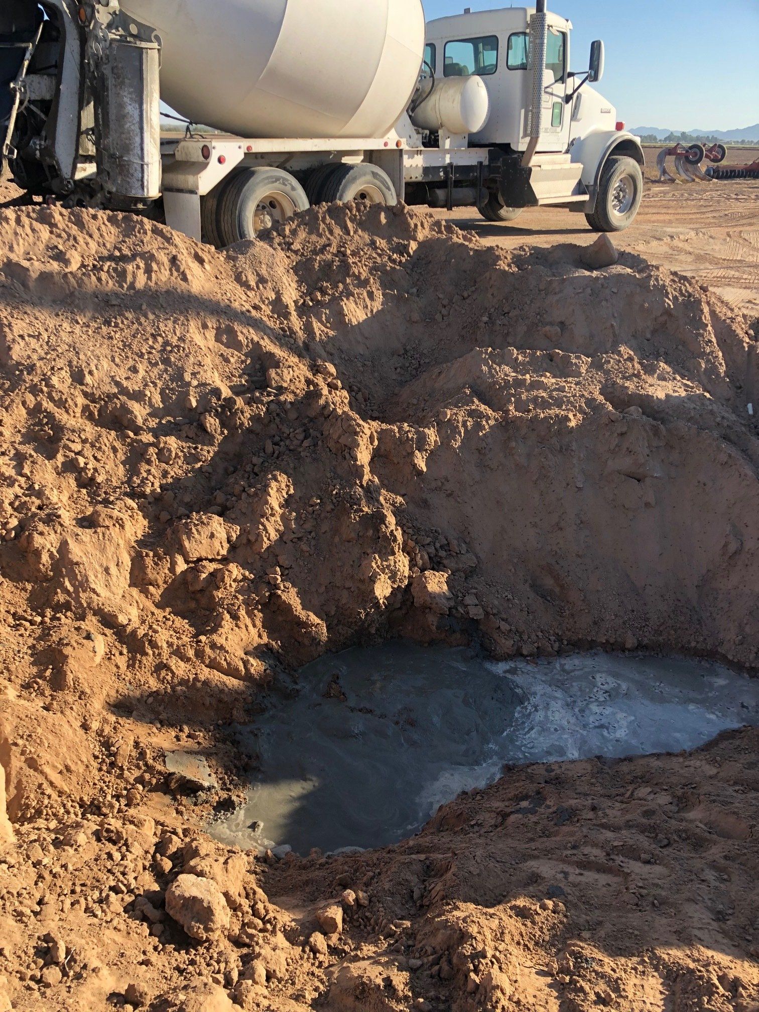 a concrete mixer truck is pouring concrete into a hole in the ground to safely abandon a well