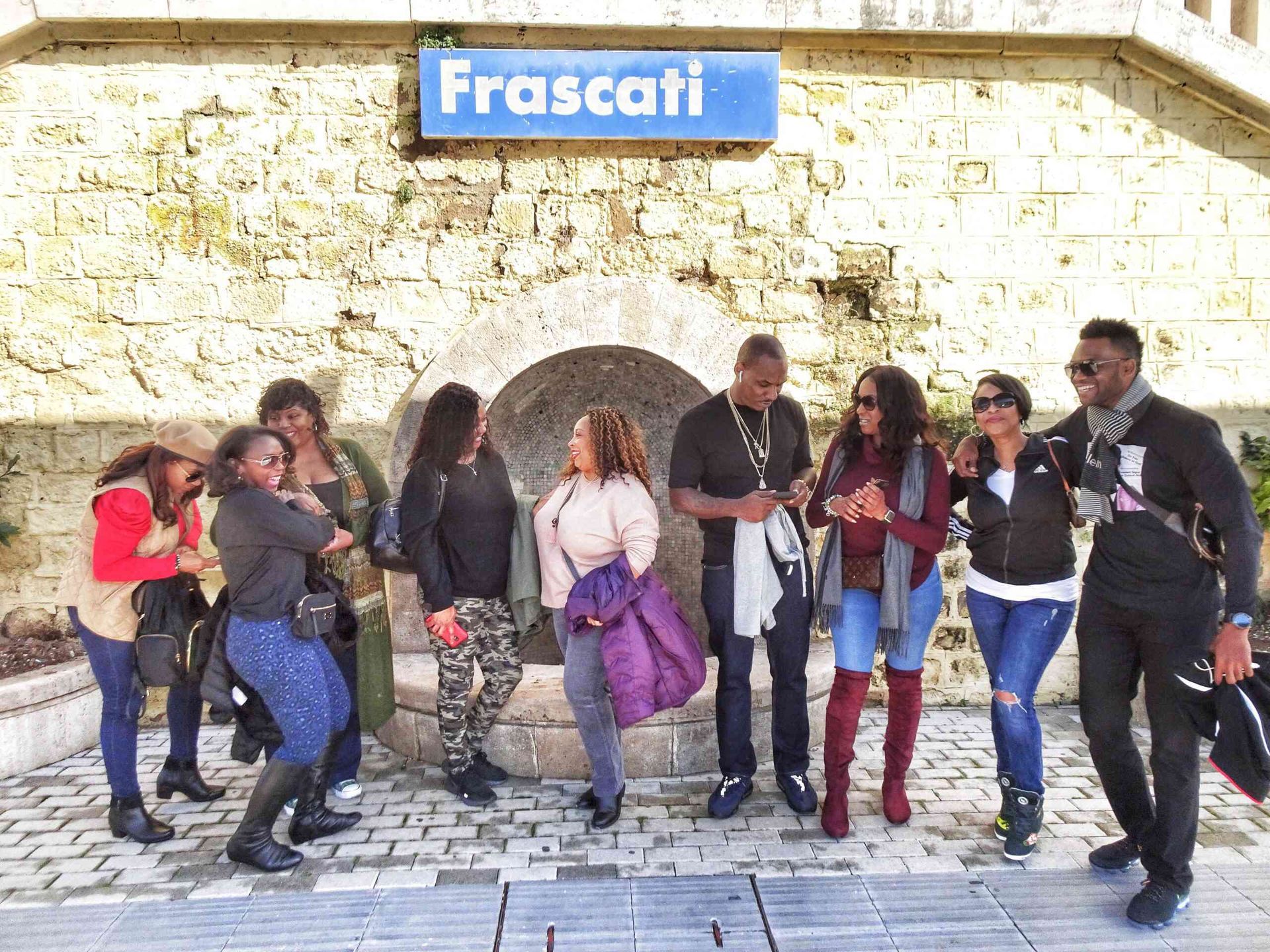 A group of people are standing in front of a sign that says frascati.