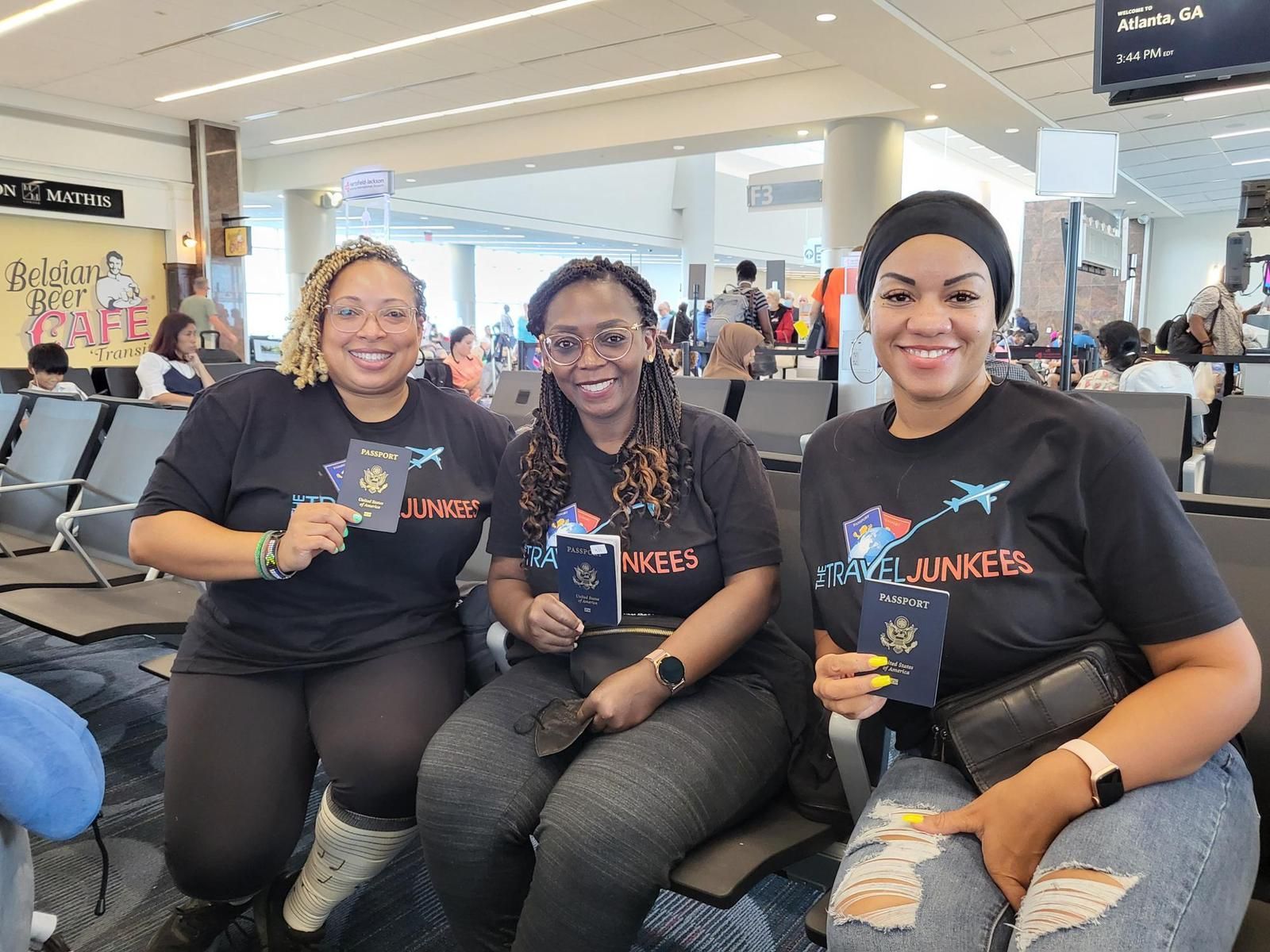 Three women are sitting in an airport holding passports.