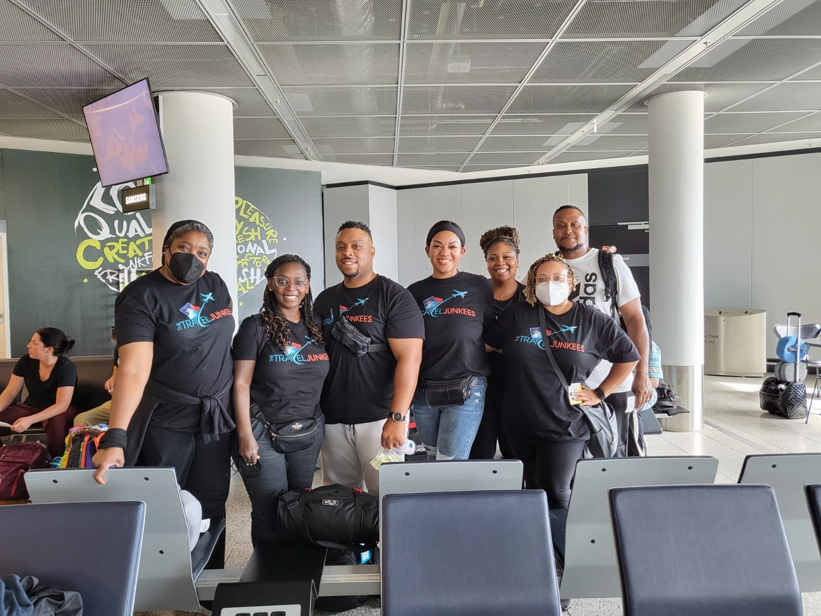 A group of people wearing masks are posing for a picture in an airport.