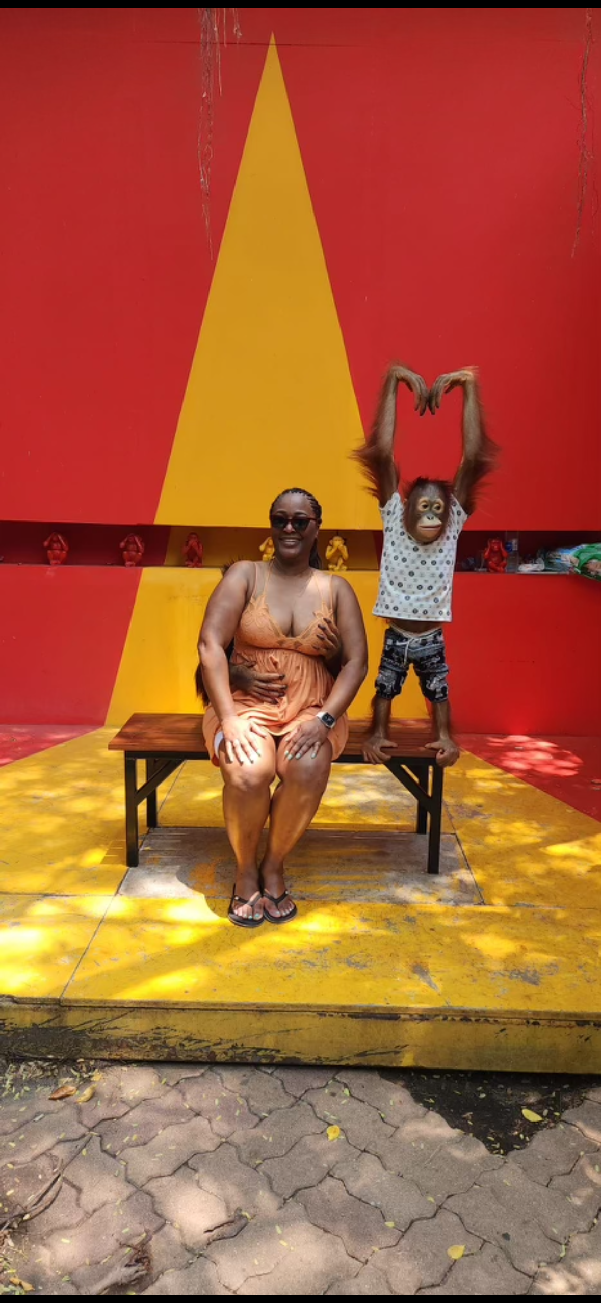 A woman and a child are sitting on a bench and making a heart shape with their hands.