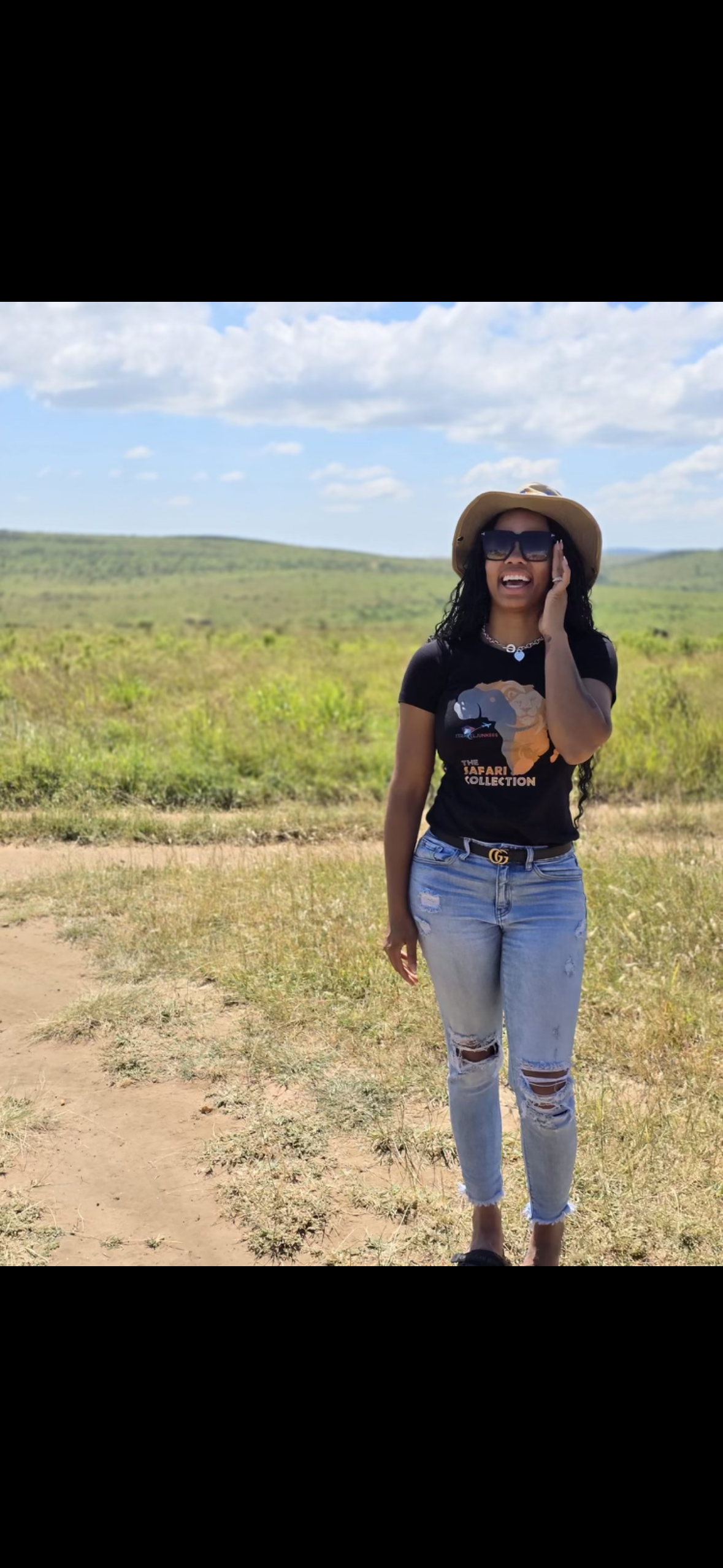 A woman wearing a hat and sunglasses is standing in a field.