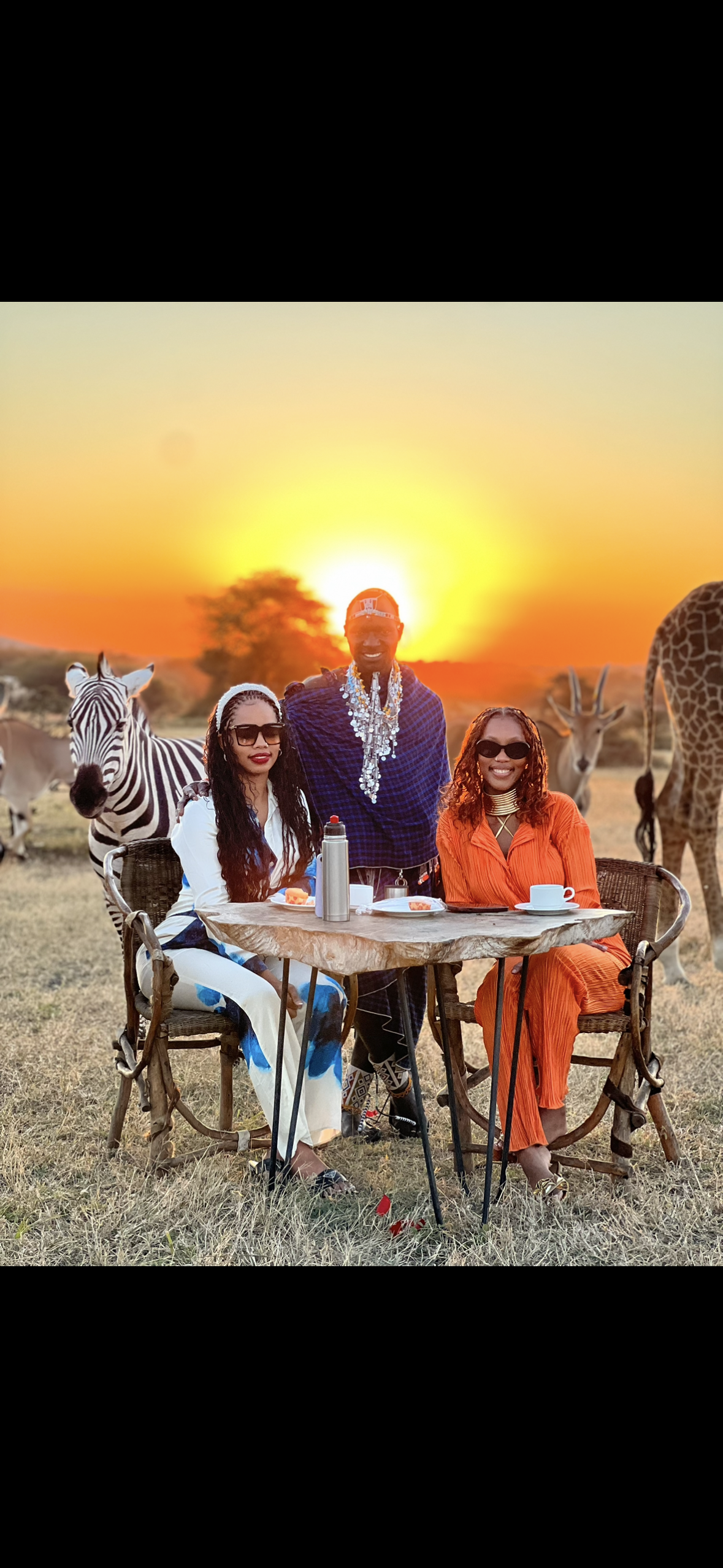 A group of people are sitting at a table in front of a zebra.