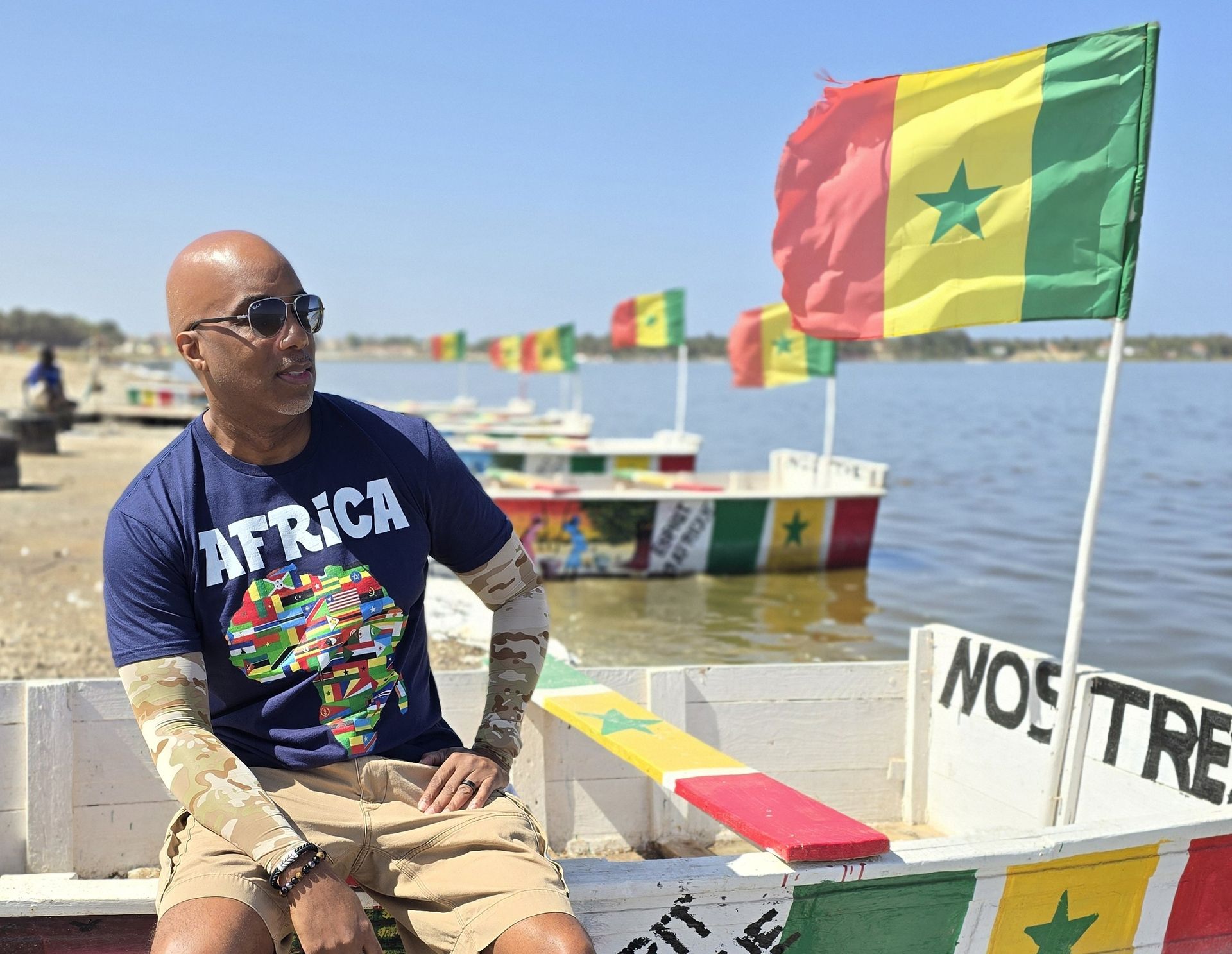 A man wearing a shirt that says africa is sitting on a boat
