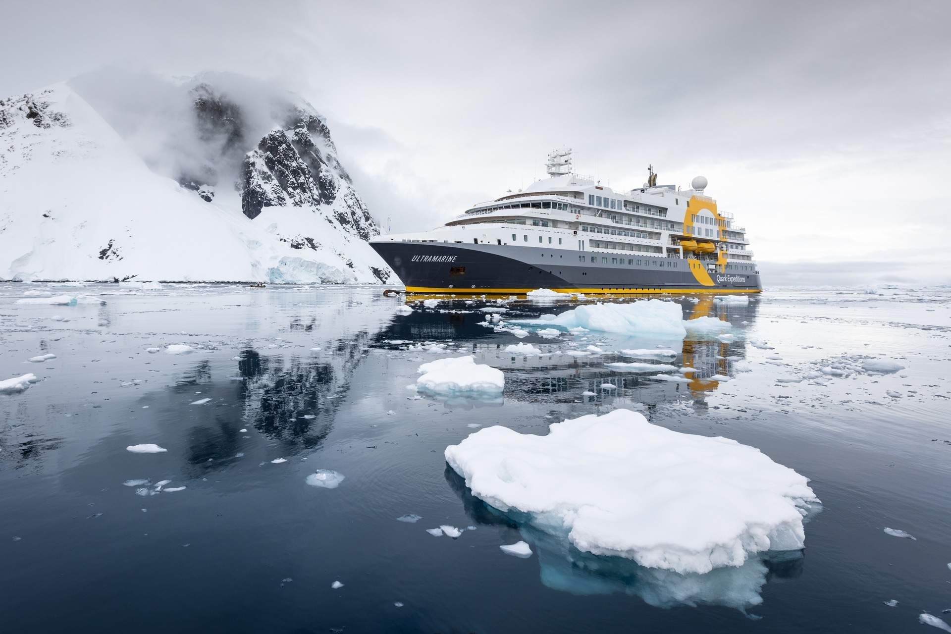 A cruise ship is docked next to a large iceberg in the ocean.