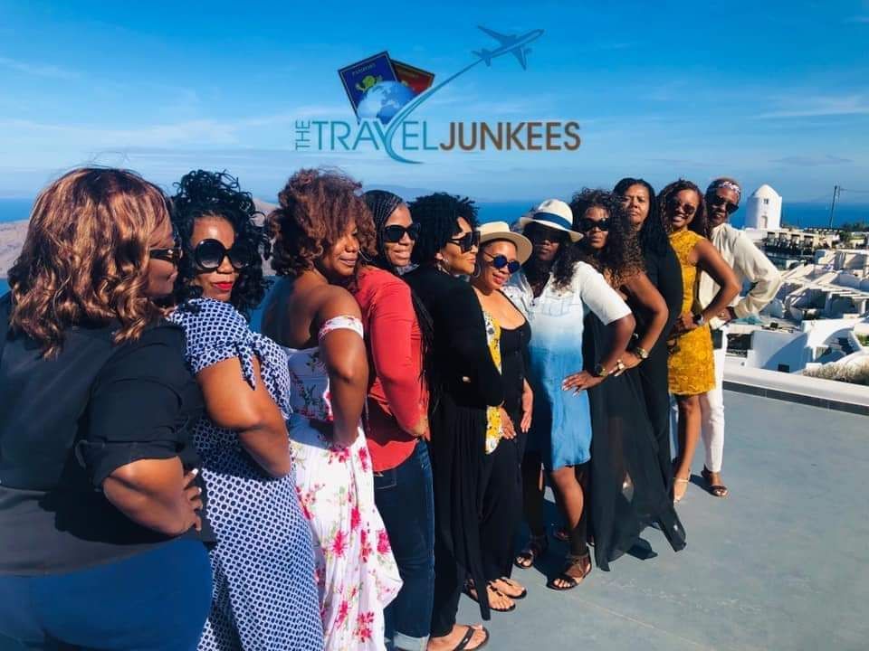A group of women are posing for a picture with the traveljunkees logo in the background.