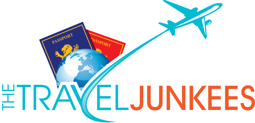 A logo for the travel junkies with a plane flying over a globe and passports