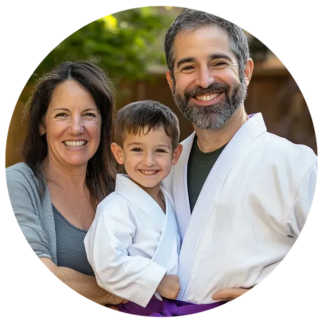 A man and woman are holding a little boy in a karate uniform.