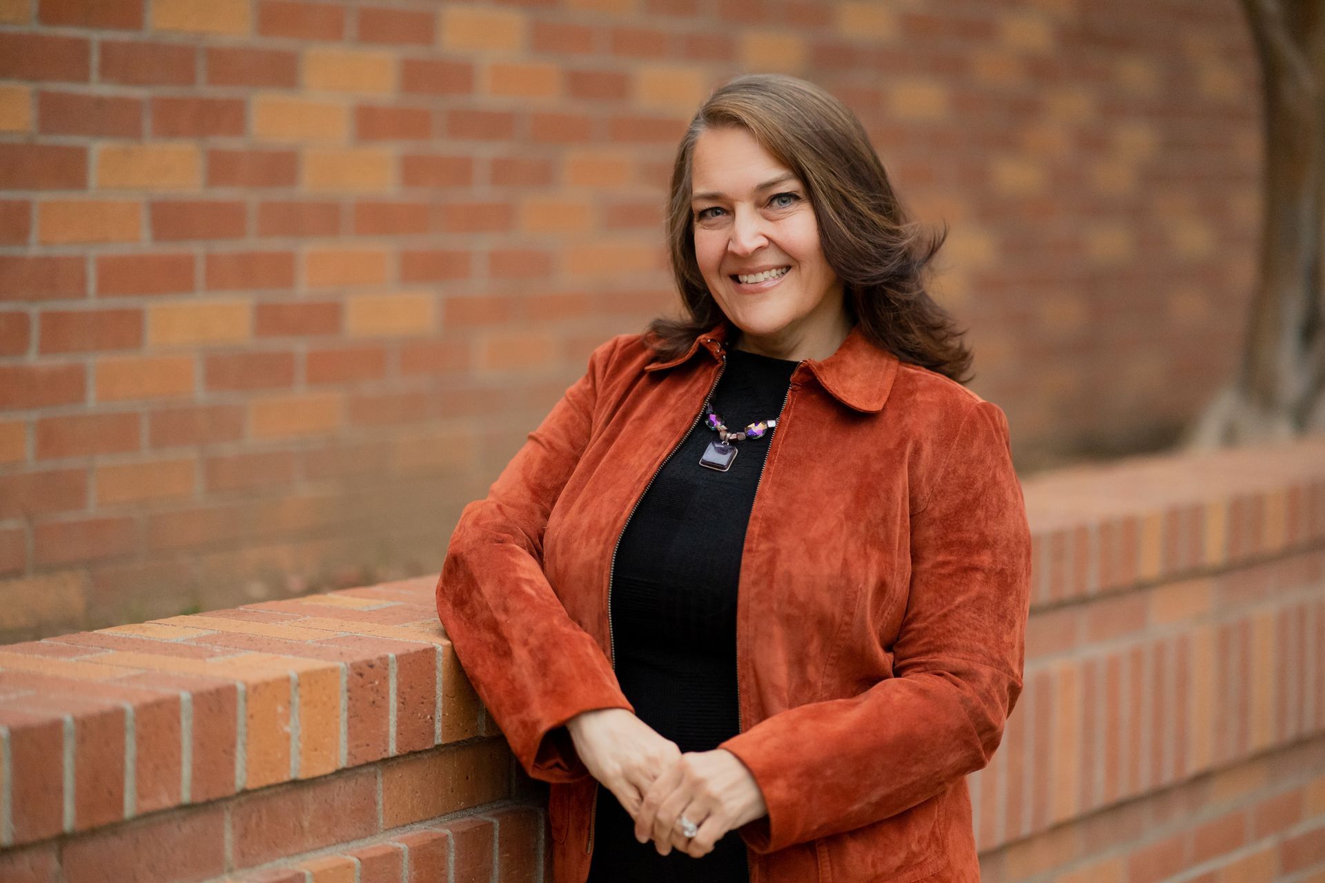 Kimberly Vaughan is leaning against a brick wall and smiling.
