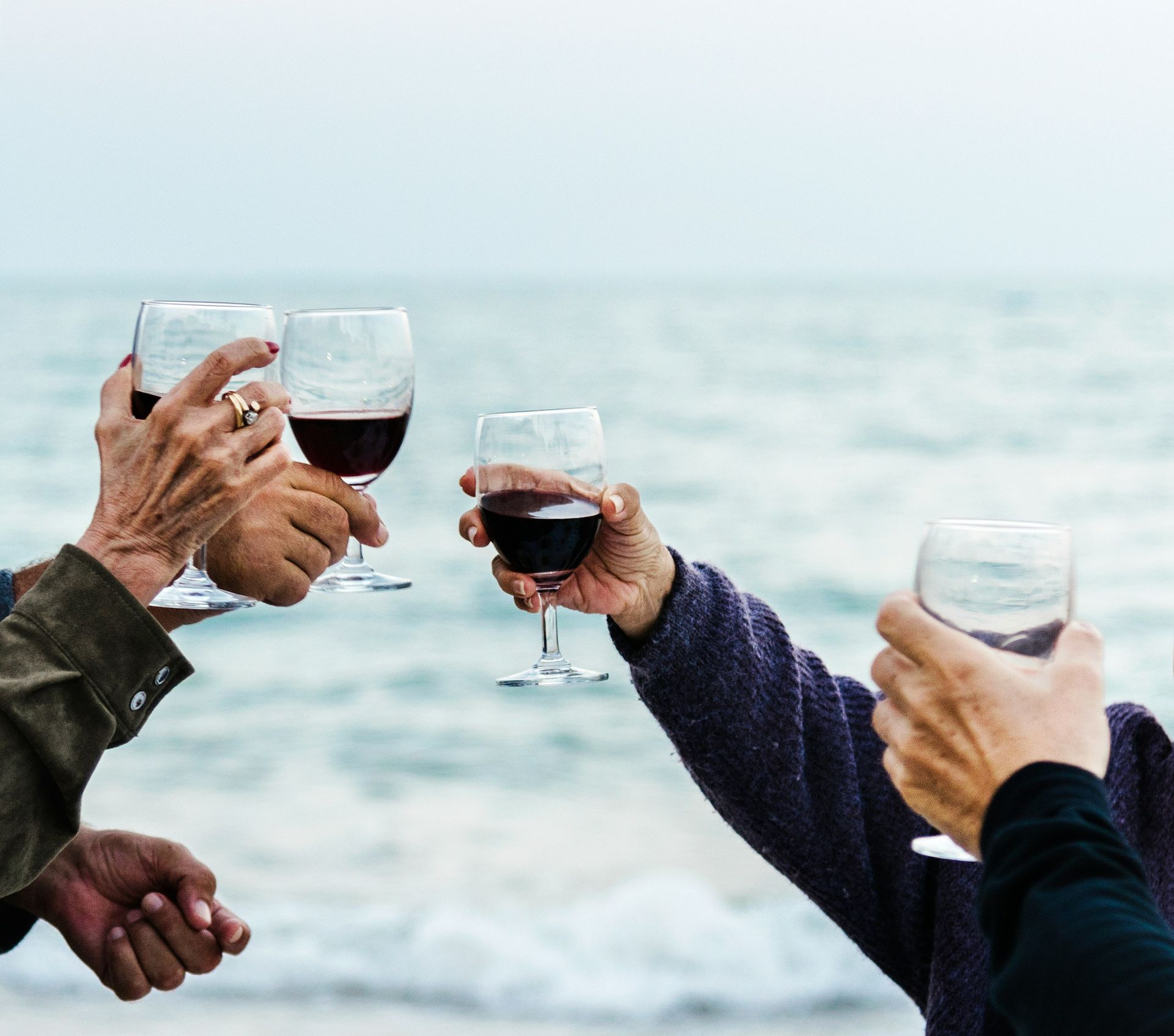 People toasting with wine glasses on a beach.