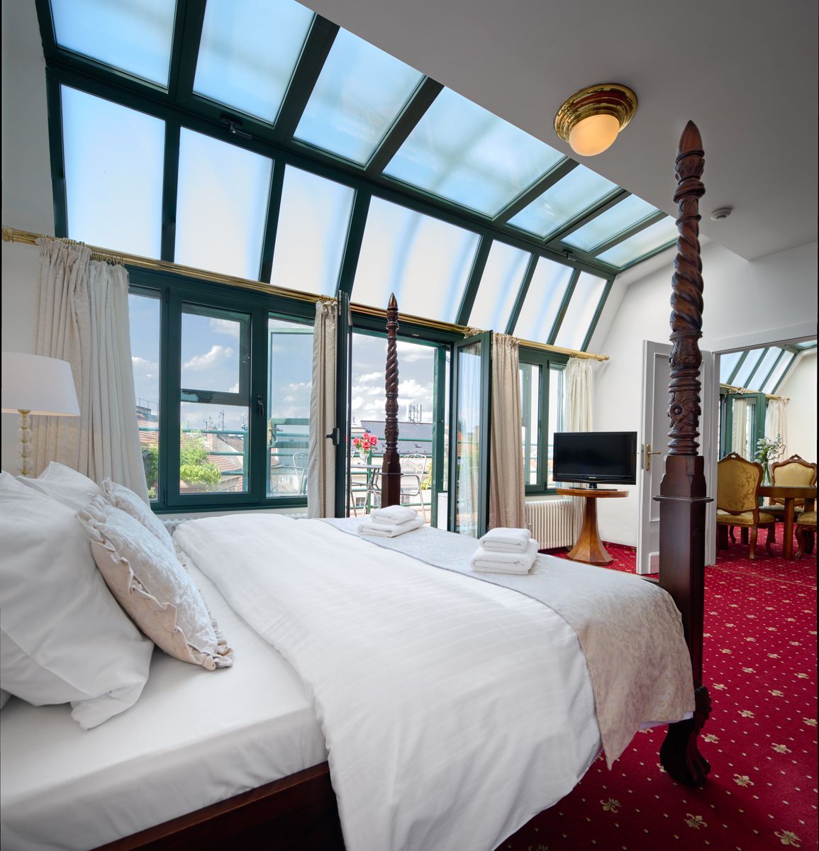Bedroom with large bed, windows, red carpet, and overhead skylight.