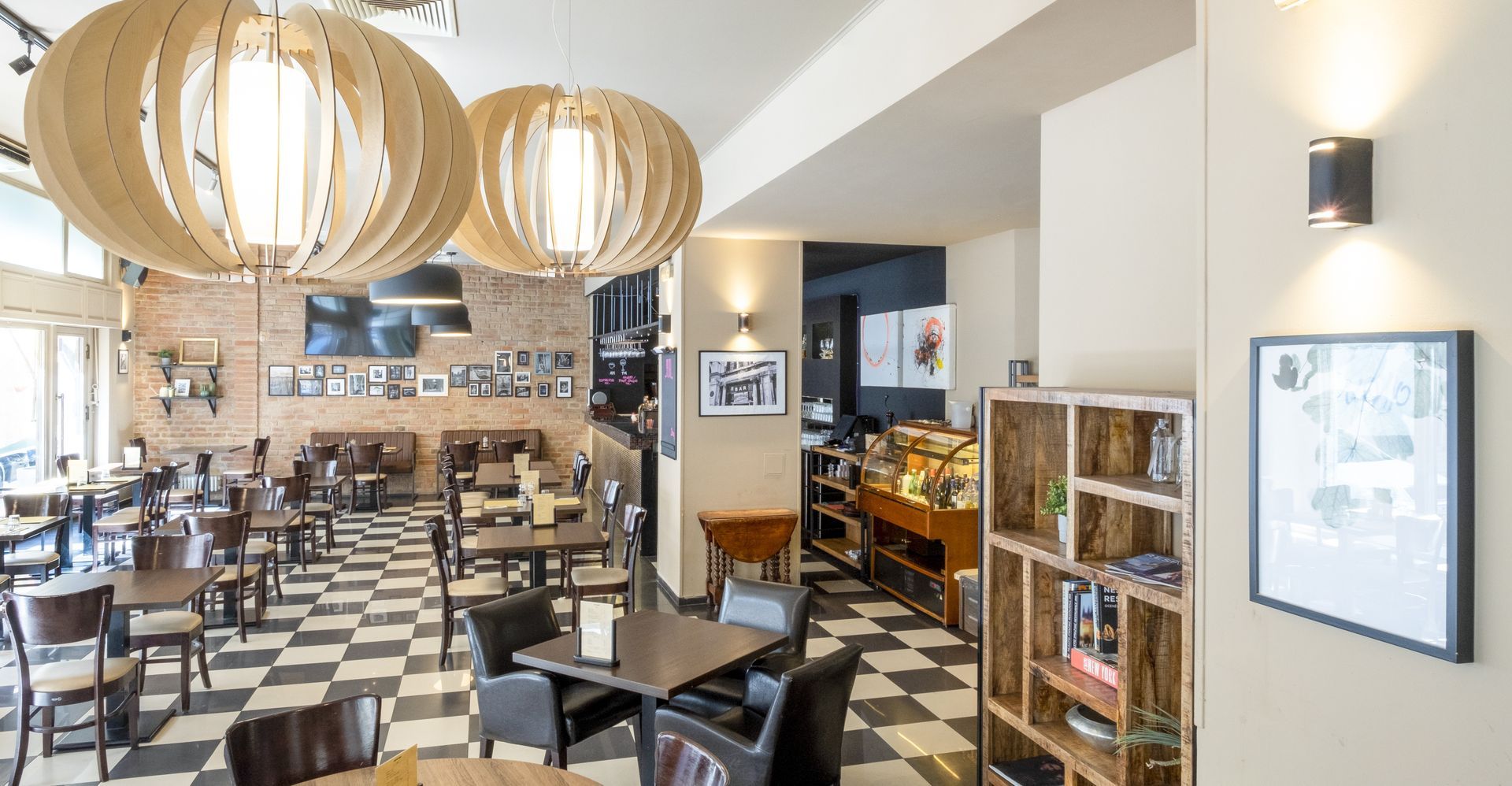Coffee shop interior with checkerboard floor, wooden pendant lights, tables, and display shelves.