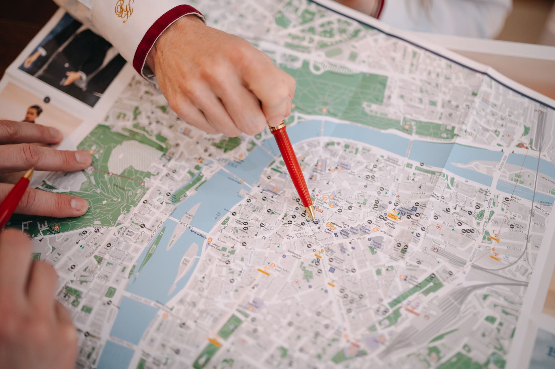 Hands pointing with red pens at a city map, possibly planning a route.